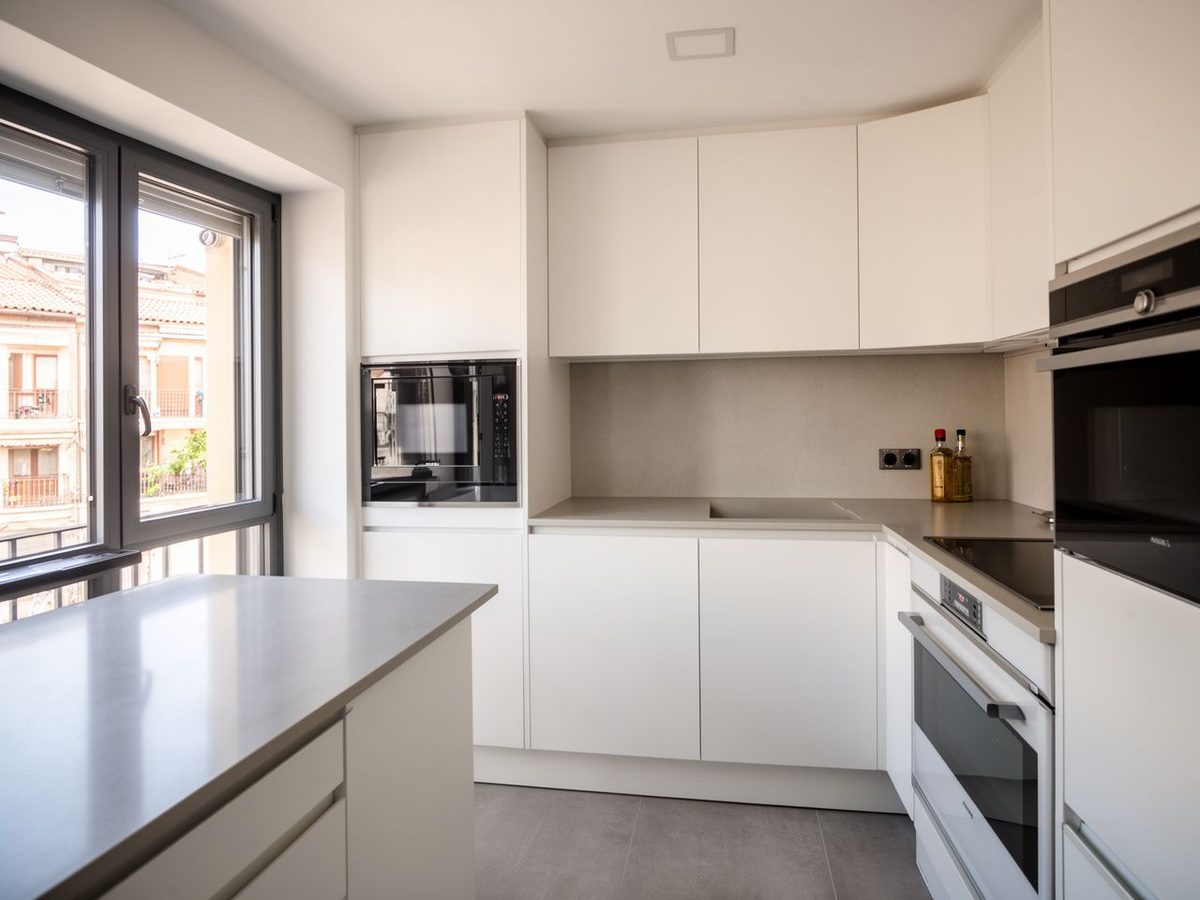 Cocina reformada con muebles blancos y electrodomésticos integrados